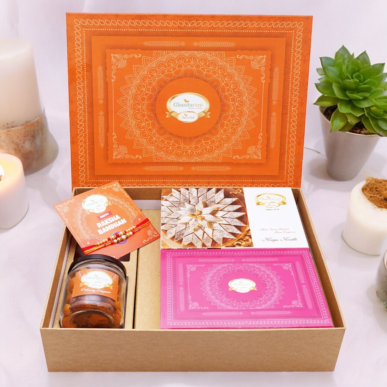 Ghasitaram Gifts Orange Hamper Box with Kaju Katli | Milk Cake | Card and Mixed Dryfruit Jar|2 Rakhis 